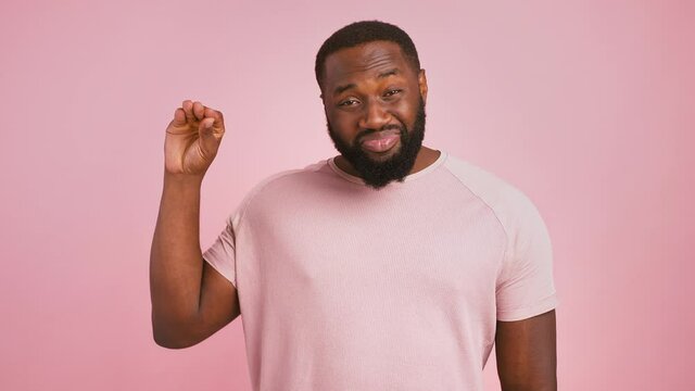 Empty promises. Annoyed african american man showing bla bla bla gesture and grimacing over pink studio background