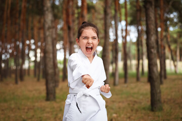Cute little girl in kimono practicing karate in forest © New Africa