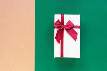 Gift in a box on beige and green combo background. Holiday concept. Top view, flat lay, copy space.