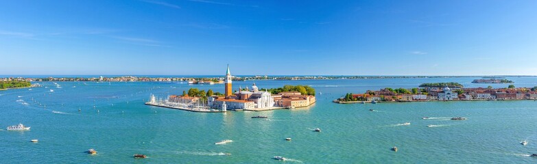 Aerial panoramic view of Venetian Lagoon with San Giorgio Maggiore island, Lido island and Giudecca island, sailing boats in Giudecca Canal, blue sky, Venice city, Italy. Panoram of Venetian Lagoon