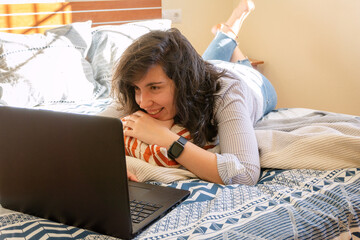Young woman learning and working at home while using the laptop on the bed