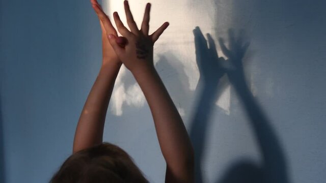 Blur shadows of child hands on wall. Game with light and shadow. Defocus spooky silhouettes of hands for Halloween concept