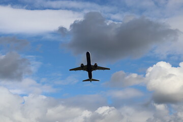 A large jet flying through a cloudy blue sky