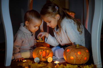Brother and sister play with pumpkins on Halloween. A boy and a girl view a pumpkin carriage in the...