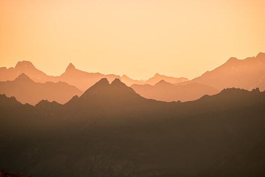 Beautiful Mountain And Sunset at swiss Alps. Dark Silhouette of Mountains on Yellow Sunrise Background © Tereza