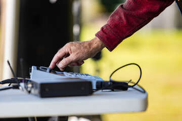 Selective focus of hands of male dj mixing sound and speaker with electrical sound equalizer by adjusting system during cultural fiesta at venue