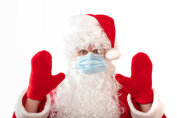 View of a man wearing a Santa Claus costume, medical mask and having his both hands up, eyes wide open, as if warning or stopping something, isolated on white background. Pandemic holiday concepts