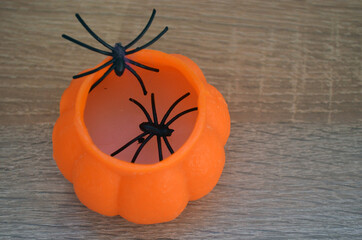A black spider crawls on a purple web and an orange pumpkin on a lilac background. Halloween. Card.