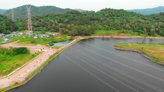 orbit drone shot  birds-eye view camera roll up transmission tower power grid power line by the lake over the mountain