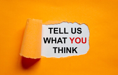 The text 'tell us what you think' appearing behind torn orange paper. Business concept. Copy space.