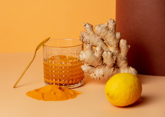 turmeric, honey, lemon and ginger next to a glass on a paper background