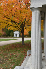 From the columns of a private estate mausoleum, another estate is seen amidst the autumn colors in a cemetery