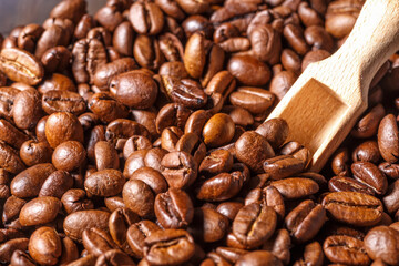 Freshly roasted coffee beans background.Dark roasted coffee beans with scoop on wooden background.