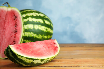 Yummy watermelons on wooden table near color wall, space for text