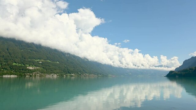 White cumulus clouds rolling above lake and hills