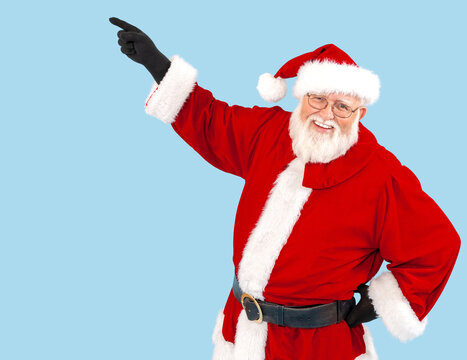 Santa Claus isolated on blue is pointing at something.