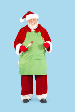 Santa Claus isolated on blue is wearing a green apron.