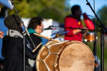 Selective focus of native sacred circle drums in cultural fiesta on stage while unrecognized...