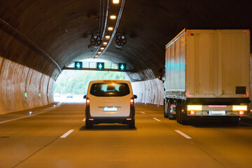 White coach pass by a speeding truck inside a highway tunnel before exciting the light