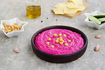 Obraz na płótnie Canvas Healthy food, beet hummus in a brown clay bowl on a gray concrete background. Served with chopped vegetables. Vegan recipes.