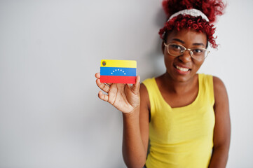 African american woman with afro hair, wear yellow singlet and eyeglasses, hold Venezuela flag isolated on white background.