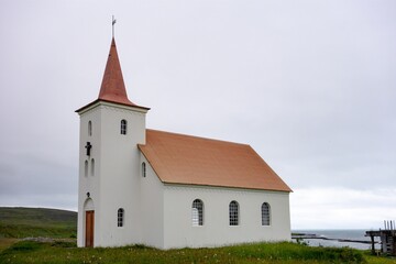 Fototapeta na wymiar White old Kollafjardarneskirkja Christian church at Western Iceland near Holmavik in cloudy weather
