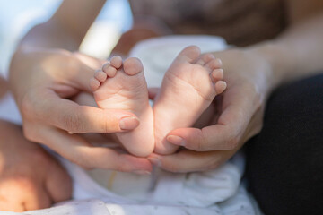 Newborn baby girl feet in mother’s hands. Outside