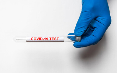 COVID-19 test inscription. Coronavirus concept on table on test tube with doctor hands in gloves,...