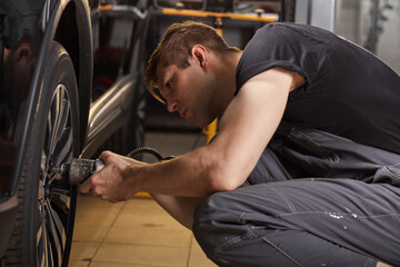 concentrated professional auto mechanic man repairs a wheel that has broken, changing
