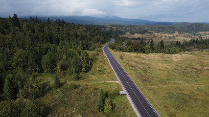 Aerial view descending over a mountain road covered by fog at sunrise