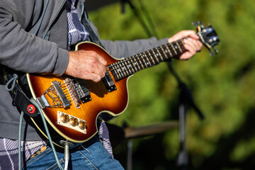Obraz premium Selective focus of young male guitarist playing electric musical instrument during cultural fiesta while performing with pick