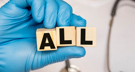 ALL Acute lymphoblastic leukemia - word from wooden blocks with letters holding by a doctor's hands in medical protective gloves. Medical concept.