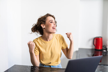 Euphoric winner woman watching a laptop on a desk winning at home