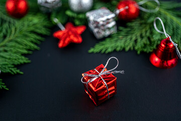 Christmas composition with red gift. Fir tree, gift and toys. Winter holiday. Space for text. Blurred focus background