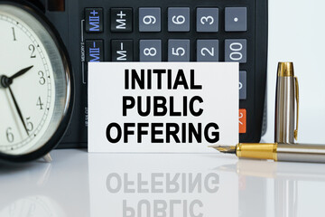 On the table there is a clock, a pen, a calculator and a business card on which the text is written...