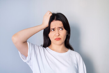 Hmm, need to think! Thoughtful confused girl scratching head having doubts, not sure contemplating with uncertain puzzled face. indoor studio shot isolated on gray background