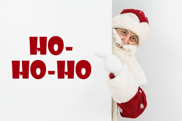 Santa Claus points his fingers at the board with the text - HO HO HO