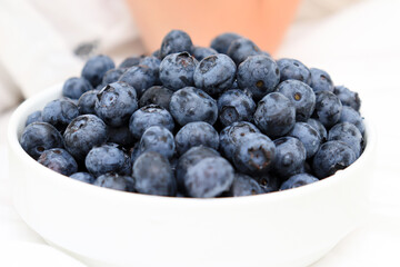 A bowl of tasty blueberry standing on a bed near the person for breakfast