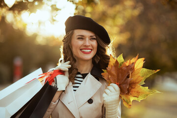 happy modern woman with shopping bags and autumn yellow leaves