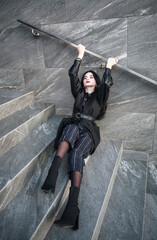 Girl in fashionable black casual clothes on background of stone wall, modern urban architecture,...