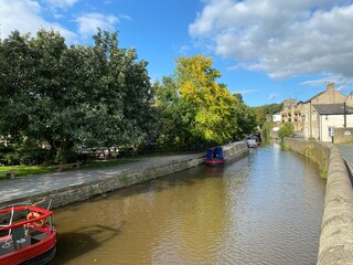 Boats on the Leeds to Liverpool canal, with old trees, and houses on the canal banks in, Skipton, Yorkshire, UK