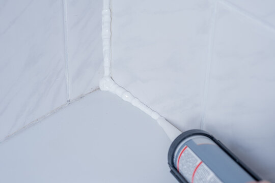 Plumber Applying silicone sealant to the tile joint