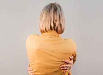 Beautiful woman standing over isolated gray background Hugging oneself happy and positive from...