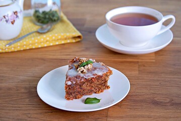Dessert, a portion of carrot cake with walnuts and almonds on a white plate. Decorated with walnuts and icing.