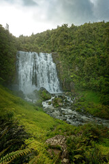 Marokopa Falls, North Island of New Zealand. Landscape scenery of the Zealand waterfall, cloudy sky ang green forest around