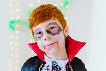 Horizontal portrait of little red haired boy dressed as a spooky vampire for Halloween. Halloween party trick or treat for children and family. Seasonal and festive concept.