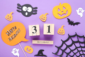 Text Happy Halloween with cube calendar, papper pumpkins, ghosts and bat on purple background