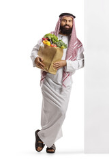 Arab man with a grocery bag standing and leaning on a wall