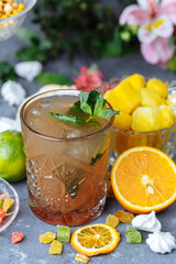 Cold refreshing pineapple cocktail with lime and mint for a hot summer day on a gray background decorated with candied fruit, mint and pineapple cubes. mojito idea, homemade lemonade with ice cubes