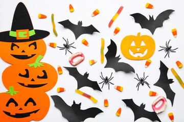 Halloween paper bats, pumpkins with candies and spiders on white background